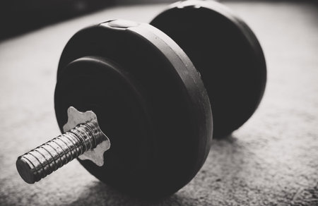Adjustable dumbbell with plate. Black and white photo.