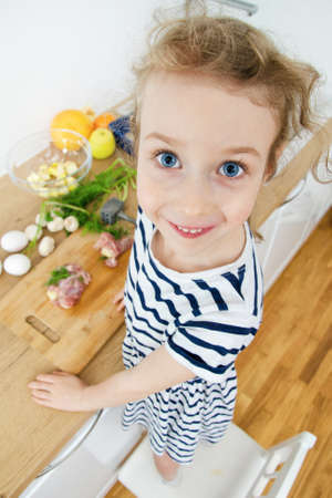 Portrait of funny cute little girl in the kitchen.の写真素材