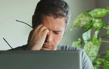 Tired man with eyes fatigue at work.の写真素材