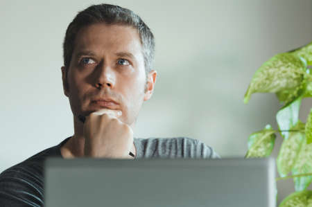Thoughtful handsome man in front of his laptop in the office.の写真素材