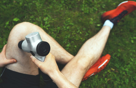 Man massaging leg with massage percussion device after workout.