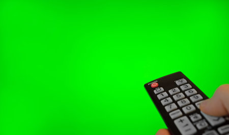Male hand with remote control pointing on TV screen. Green chroma key.