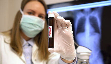 Virologist in laboratory holding Covid-19 sample tube. Coronavirus concept.