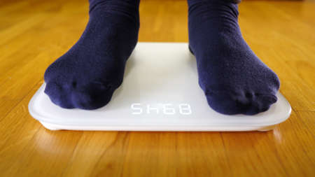 Legs on the scales. Man checking his weight.の写真素材