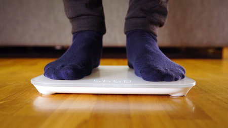 Legs on the scales. Man checking his weight.