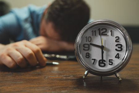 The clock shows half past nine in the evening. Man fell asleep at work.の写真素材