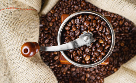 Vintage old coffee grinder with coffee beans in bag.