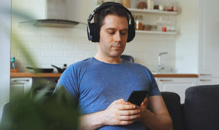 Man with headphones listening to music on the couch.の写真素材