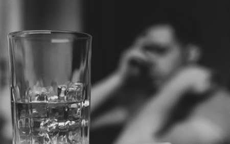 Exhausted drunk man with glass of whiskey. Alcoholism concept.の写真素材