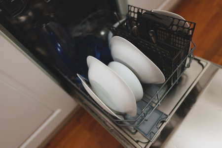 Open dishwasher with washed dishes in the kitchen.の写真素材