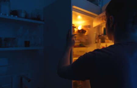 Man looking for food in refrigerator at night.の写真素材