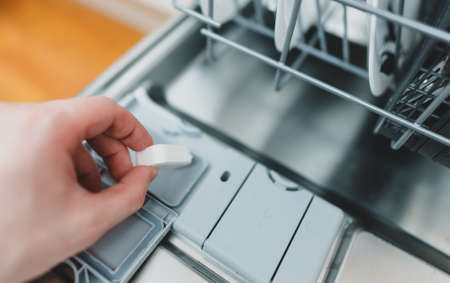 Man putting detergent tablet into dishwasher.の写真素材