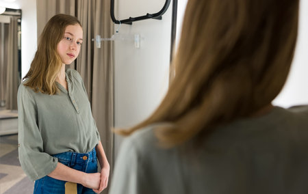 Tween girl standing in fitting room in clothing store.