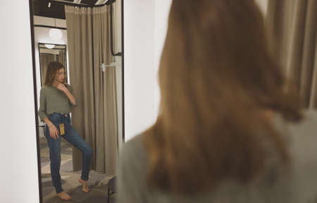 Tween girl standing in fitting room in clothing store.の写真素材