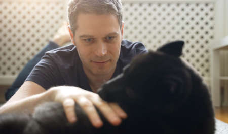 Man playing with his Schipperke dog.の写真素材