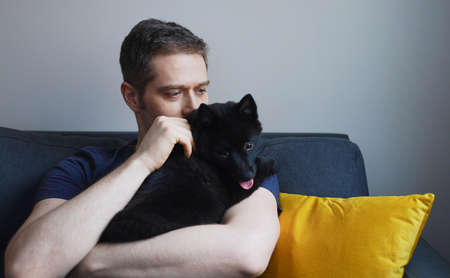 Man with his Schipperke dog at home.の写真素材