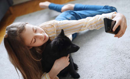 Tween girl with her new puppy doing selfie with smartphone.の写真素材