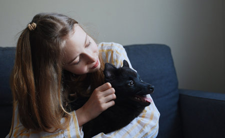 Tween girl playing with puppy at home.