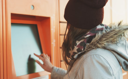 Woman picks up mail from automated self-service post terminal machine.の写真素材