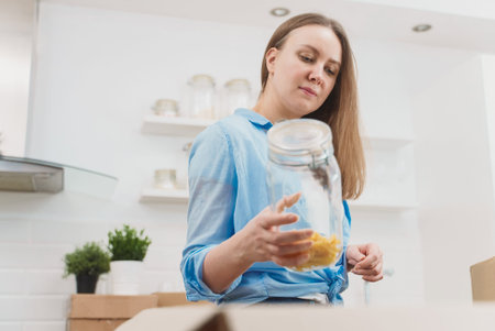 Woman arranges kitchen utensils after moving to new apartment.
