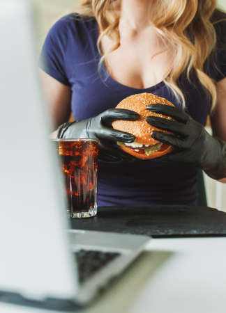 Woman eating rustic hamburger at workplace.の写真素材