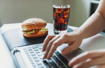 Woman and hamburger at workplace. Eternal rush concept.の写真素材