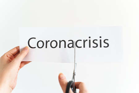 Woman cuts the word corona crisis with scissors.の写真素材