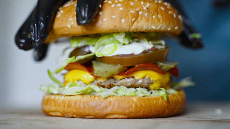 Chef in gloves presses down the finished hamburger.の写真素材
