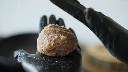 Woman chef in black gloves prepares cutlets.の写真素材