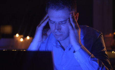 Tired overworked man working on laptop pc at late night.の写真素材
