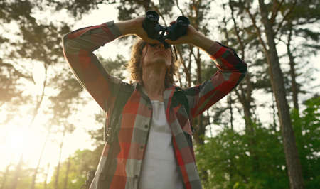 Man with rucksack and binoculars in the forest.の写真素材