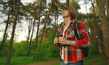 Man with rucksack and binoculars in the forest.の写真素材