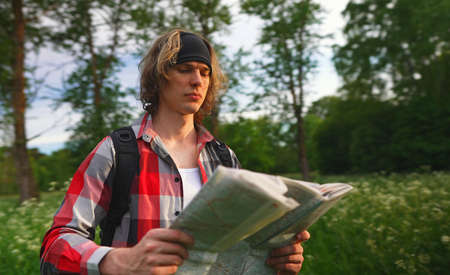 Male tourist with map and backpack in the forest.の写真素材