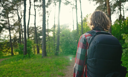 Man with backpack and sunglasses in the woods. Arc shoot.