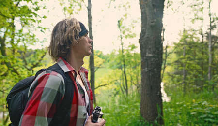 Man with rucksack and binoculars in the forest.の写真素材