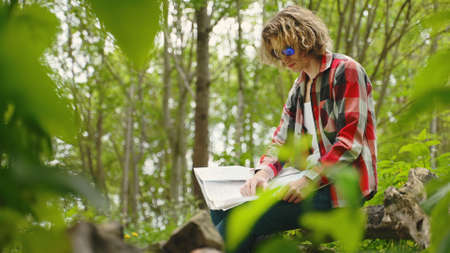 Man sits with compass and map. Orienteering.の写真素材