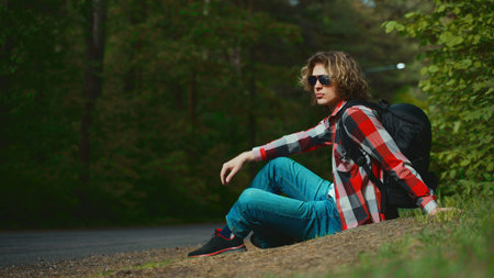 Male tourist resting by the road in woods.