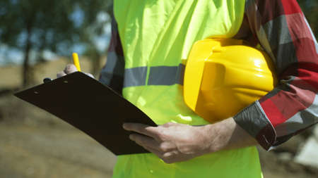Builder with hard hat inspects construction site. Close-up.の写真素材