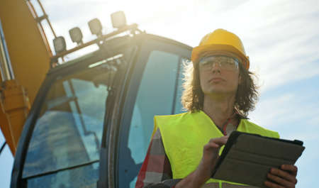 Excavator operator in hard hat using tablet pc.の写真素材