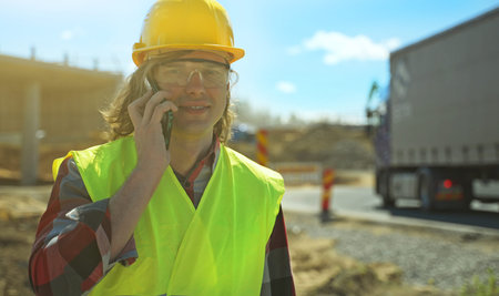 Builder talking by smartphone at construction site.