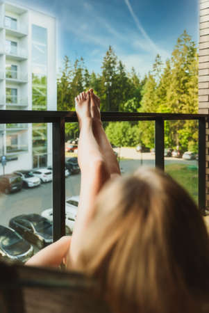 Woman is enjoying white wine on the balcony.の写真素材