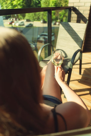 Woman is enjoying white wine on the balcony.