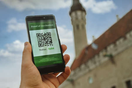 Hand holding smartphone with coronavirus vaccine passport app. Status is valid.の写真素材