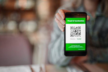 Woman showing smartphone app with certificate of immunization in restaurant. Status is valid.