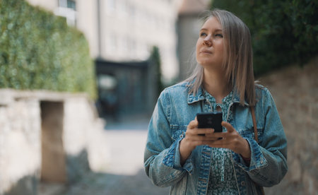 Female tourist with smartphone walks through the old city.