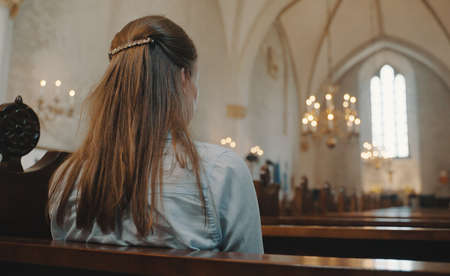 Woman is sitting in a church and praying.の写真素材