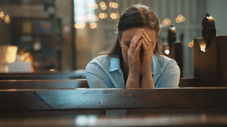 Woman is sitting in a church and praying.の写真素材