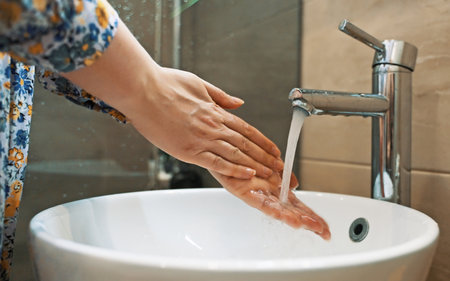Woman washes her hands in the sink.の写真素材