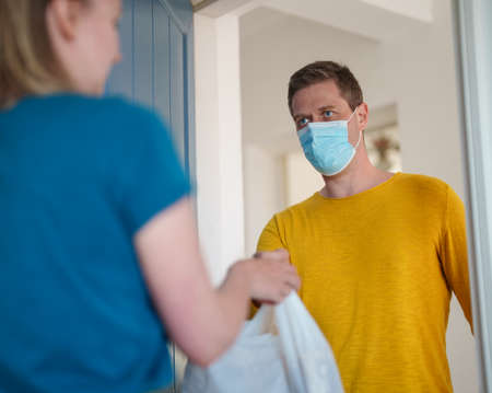 Masked man delivers food during pandemic.の写真素材