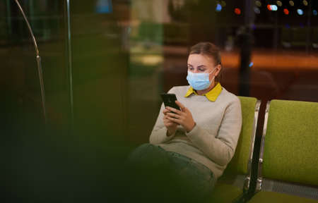Woman in medical mask waiting for her check-in at the airport.の写真素材
